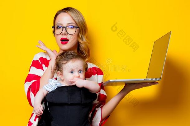 小的婴儿采用搬运人和母亲和便携式电脑