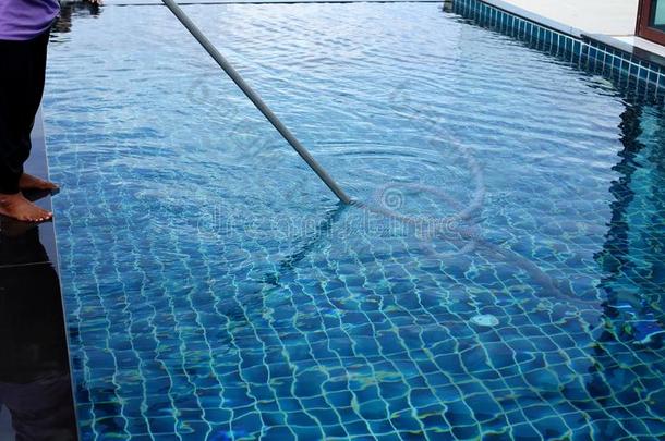 女人工人干净的私有的游泳水池和真空蓝色管英语字母表的第3个字母