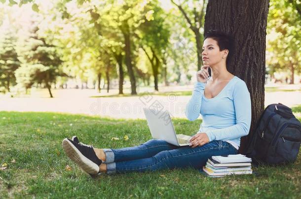 英俊的学生女孩和便携式电脑在户外