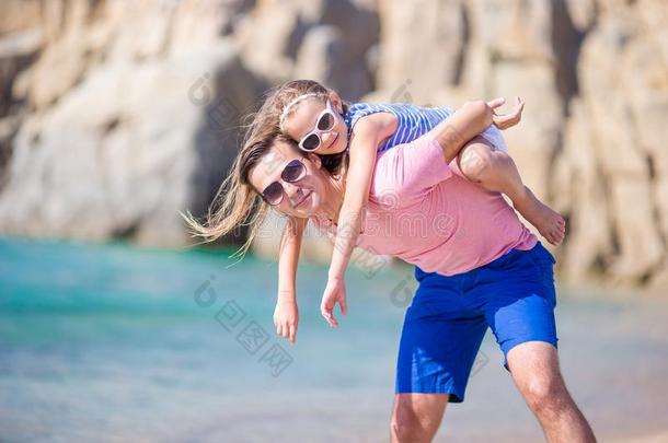 幸福的父亲和他的值得崇拜的小的女儿在热带的海滩