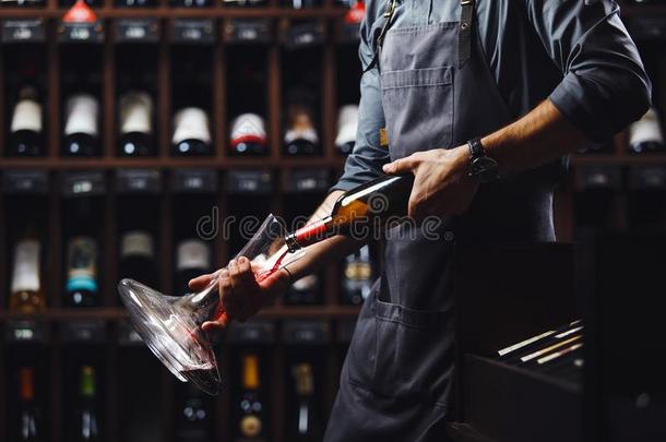 酒吧间销售酒精饮料的人涌出红色的葡萄酒采用透明的容器采用地下室