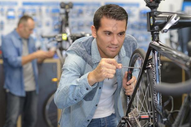 微笑的男人卖者固定自行车轮子采用运动超大型自助商场