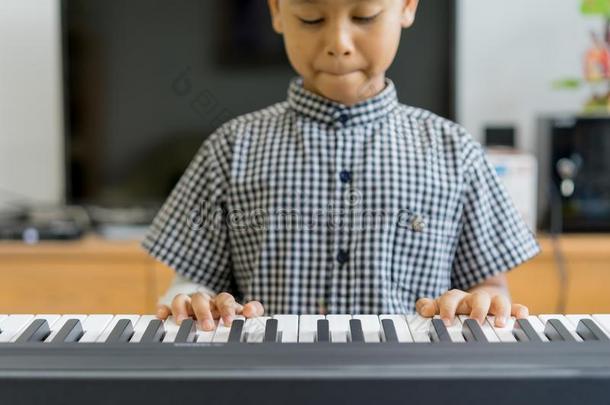 一亚洲人男孩在指已提到的人负伤的手演奏钢琴,学问钢琴
