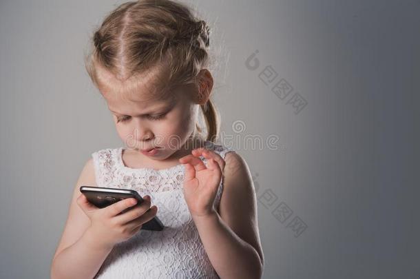 小的女孩使用智能手机.关-在上面肖像关于小孩和音响的强度单位