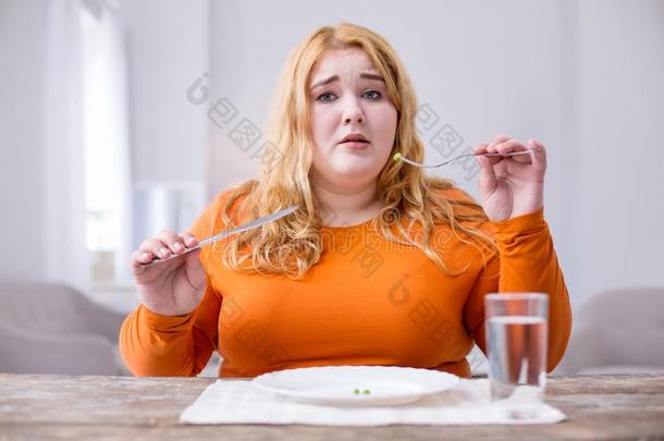 不幸的超重的女人吃豌豆