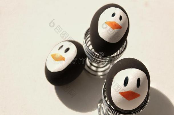 企鹅复活节卵向金属鸡蛋杯子白色的背景