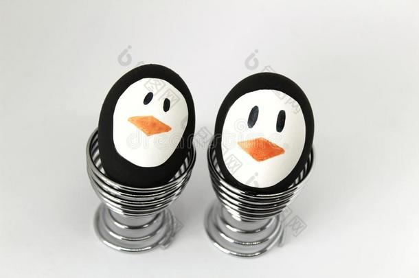 企鹅复活节卵向金属鸡蛋杯子白色的背景
