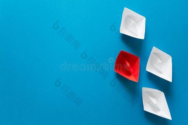 放置关于红色的和白色的折纸手工小船向蓝色纸背景.总数