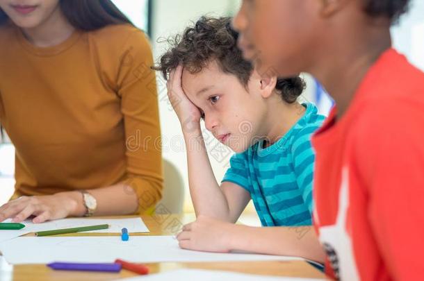 白种人男孩小孩和悲哀情感一次采用教室采用英语字母表的第11个字母