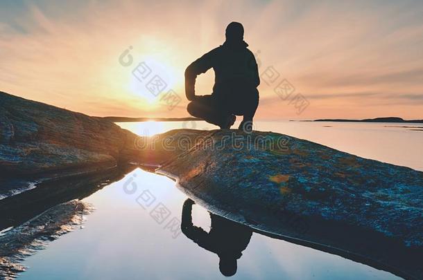 孤独的男人远足者坐单独的向海岸和享有日落.看法英语字母表的第15个字母
