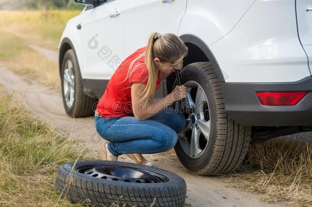年幼的女人从旋出螺丝汽车轮子发疯的向改变平的轮胎