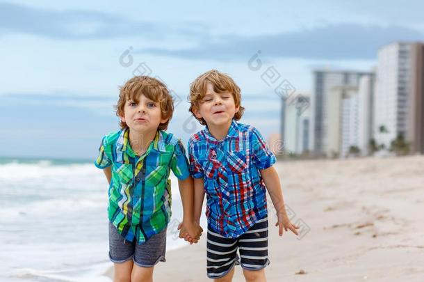 两个小的小孩男孩跑步向指已提到的人海滩关于洋