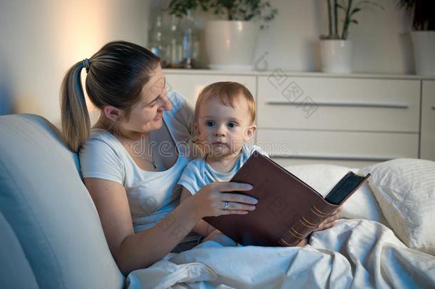 幸福的微笑的母亲阅<strong>读故事</strong>向她婴儿儿子在夜