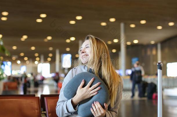 微笑的女人一次和颈枕头和旅行小皮包采用机场walk-roundinspection巡查