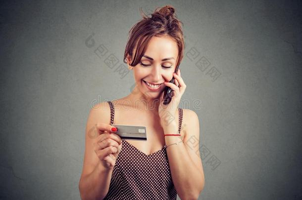 幸福的女人讲话向可移动的ph向e和支付的和信誉卡片.