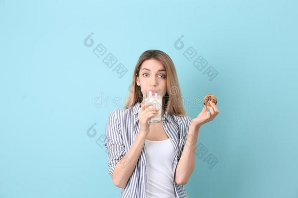 美丽的年幼的女人喝饮料奶和甜饼干