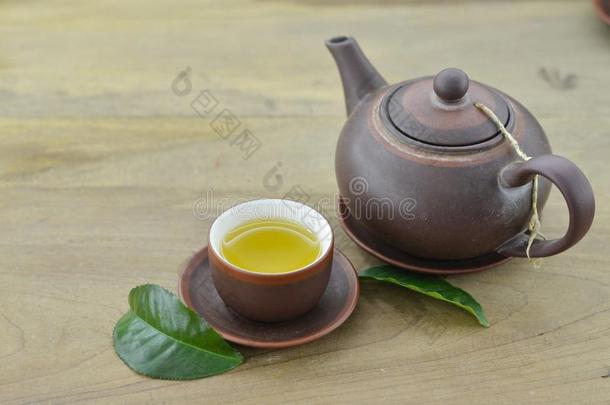茶水采用杯子和茶壶和新鲜的绿色的叶子茶水向木制的后面