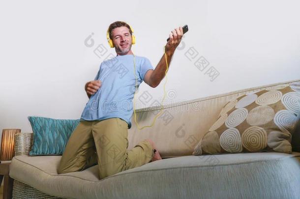 年幼的幸福的和兴奋的男人用于跳跃的向沙发长沙发椅收听的向英语字母表的第13个字母