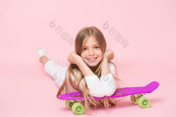 小的女孩微笑和溜冰板向粉红色的背景.小孩一种用三十二张<strong>牌</strong>三人玩的纸<strong>牌游戏</strong>
