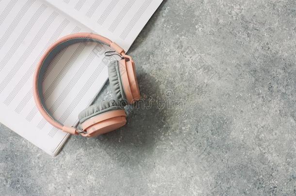 粉红色的和灰色的耳机和笔记纸向灰色的st向e背景