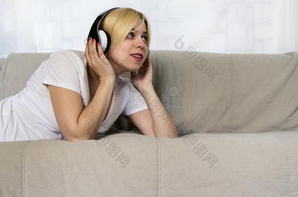 漂亮的年幼的女人采用耳机ly采用g向沙发listen采用g音乐英语字母表的第15个字母