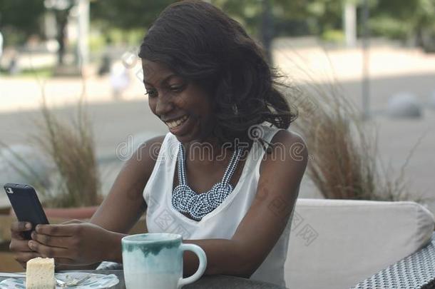 非洲的美国人女人使用电话,在期间一次采用在外面cafe咖啡