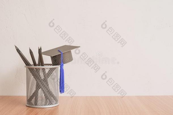 毕业盖和黑的铅笔向白色的墙背景-背