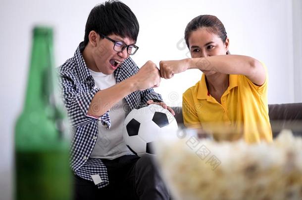 年幼的亚洲人对爱观察足球比赛向television电视机和喝彩