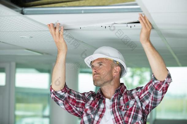 男人安装暂停的天花板采用房屋