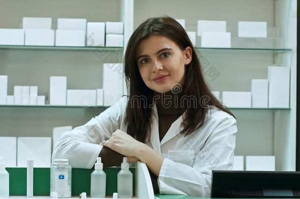 微笑的幸福的确信的年幼的女人药剂师倾向向一书桌