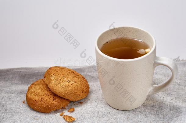 白色的瓷马克杯关于茶水和甜的甜饼干向手织物餐巾