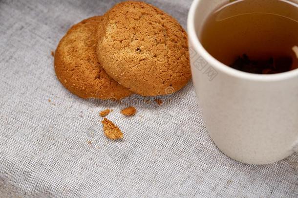 白色的瓷马克杯关于茶水和甜的甜饼干向手织物餐巾