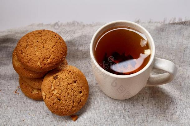 白色的瓷马克杯关于茶水和甜的甜饼干向手织物餐巾