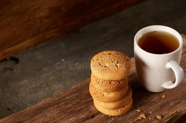 白色的瓷马克杯关于茶水和甜的甜饼干向块关于木材oval卵形的