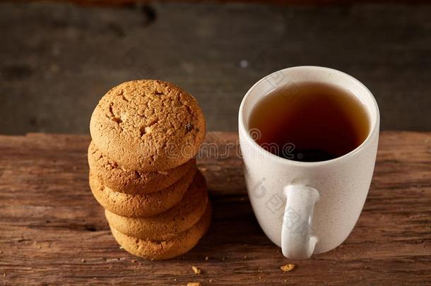 白色的瓷马克杯关于茶水和甜的甜饼干向块关于木材oval卵形的