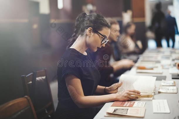年幼的黑头发的妇女女孩和眼镜和黑的口红阅读书
