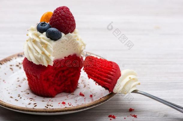 咬纸杯蛋糕红色的丝绒和白色的乳霜