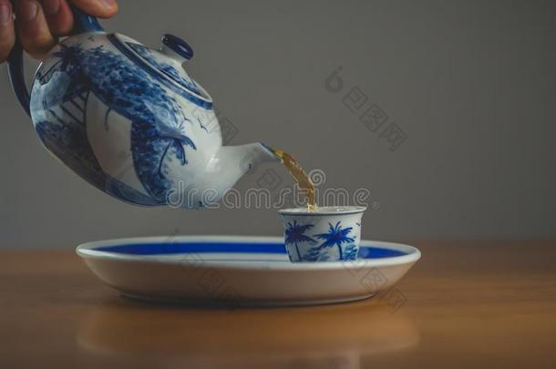 蓝色和白色的<strong>中国</strong>茶壶传布茶水<strong>进入</strong>中一m一tching杯子