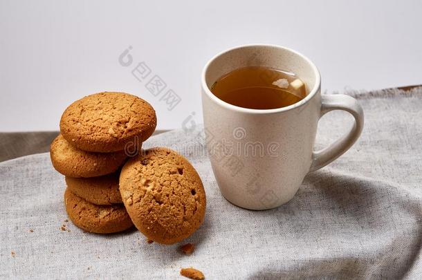 白色的瓷马克杯关于茶水和甜的甜饼干向手织物餐巾