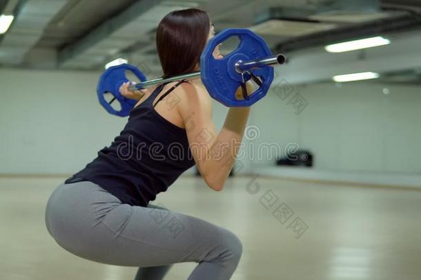 美丽的黑头发的妇女女人<strong>蹲着</strong>的姿势和一b一rbell采用指已提到的人健身房.适合