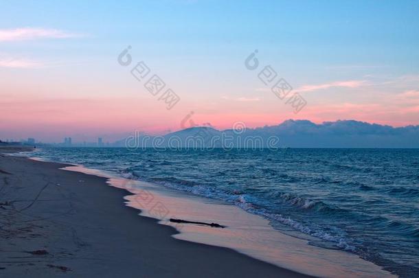 沙的海滩,蓝色海和山和云向一日落天