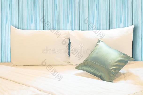 白色的枕头和绿色的枕头向床和和皱纹凌乱的蓝
