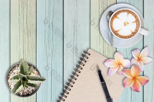 仙人掌,人造喷泉笔,花和咖啡豆拿铁咖啡向木制的表,