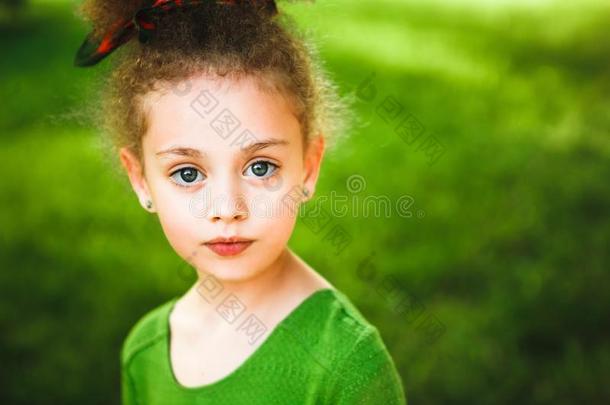 一小的,有卷发的女孩采用一绿色的衣服.