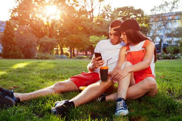 年幼的低到臀部的对使用智能手机采用夏公园在日落.