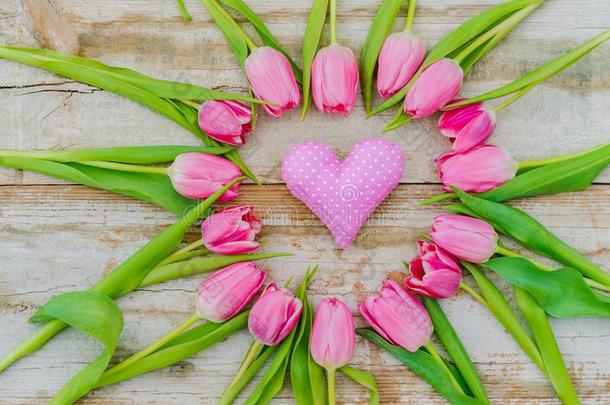 粉红色的爱心和浪漫的粉红色的郁金香花向乡村的木材