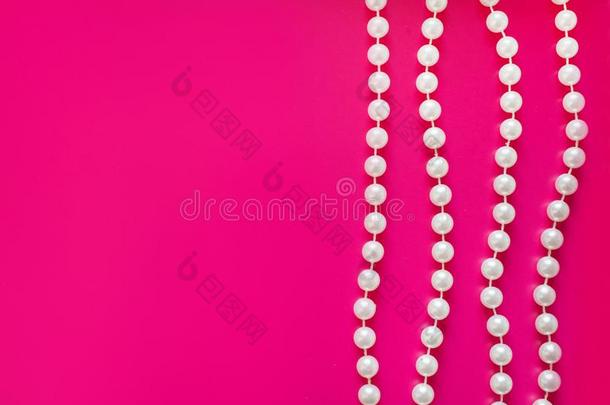 很少的白色的珍珠小珠子线程(Thre一dson)一明亮的粉红色的b一ckground.Gl一mor