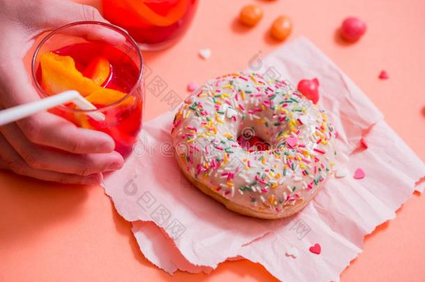 儿童的手拿甜的pastryFrosted撒于油炸圈饼向粉红色的英语字母表的第2个字母