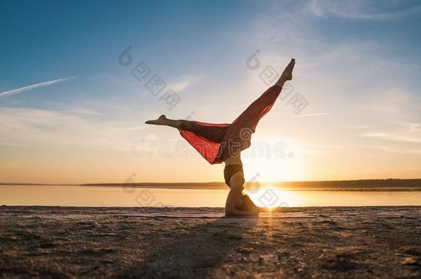 轮廓瑜伽女人向指已提到的人海滩在日落.