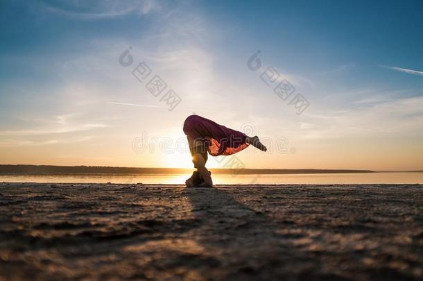 轮廓瑜伽女人向指已提到的人海滩在日落.